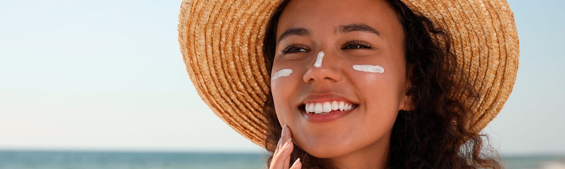 Mulher jovem na praia passando protetor solar com alto FPS