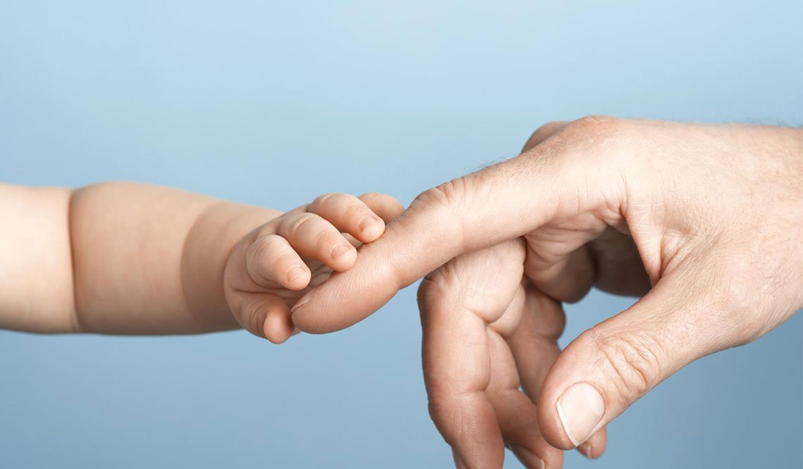 Mão de bebe e mão de adulto lado a lado